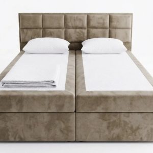 Taupe boxspringbed met panelen hoofdbord, twee witte kussens en wit beddengoed van voren
