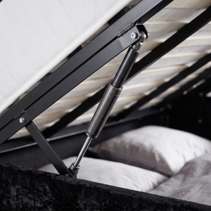 Detail van het gasliftmechanisme van een opbergbed met opgeklapt matras en opbergruimte